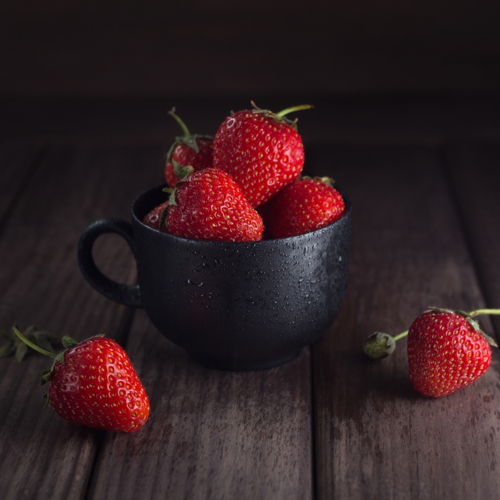 Черная чашка с красными ягодами клубники