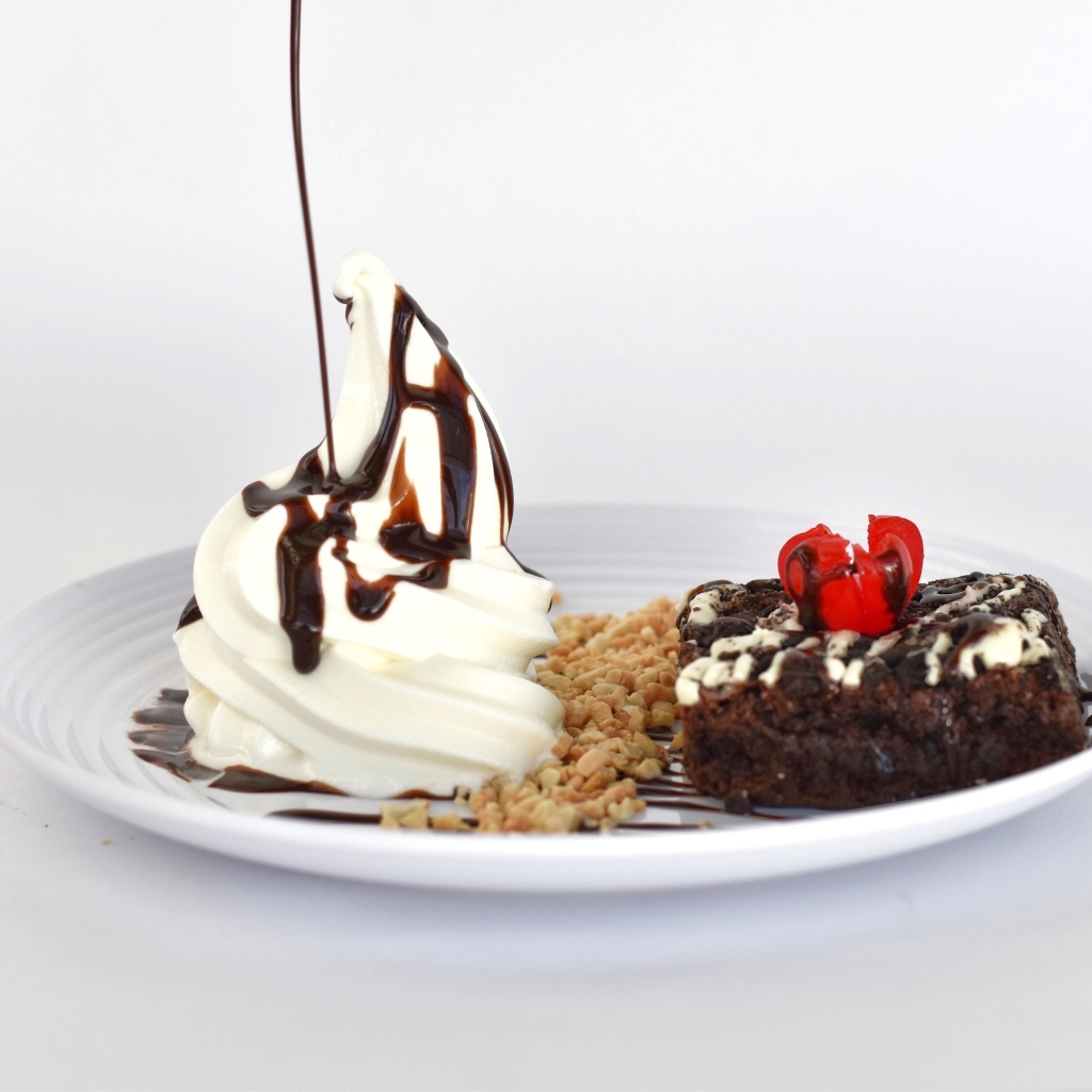 Пирожное со взбитыми сливками на тарелке на белом фоне