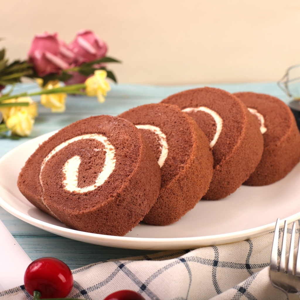 Шоколадный бисквитный рулет с кремом на тарелке