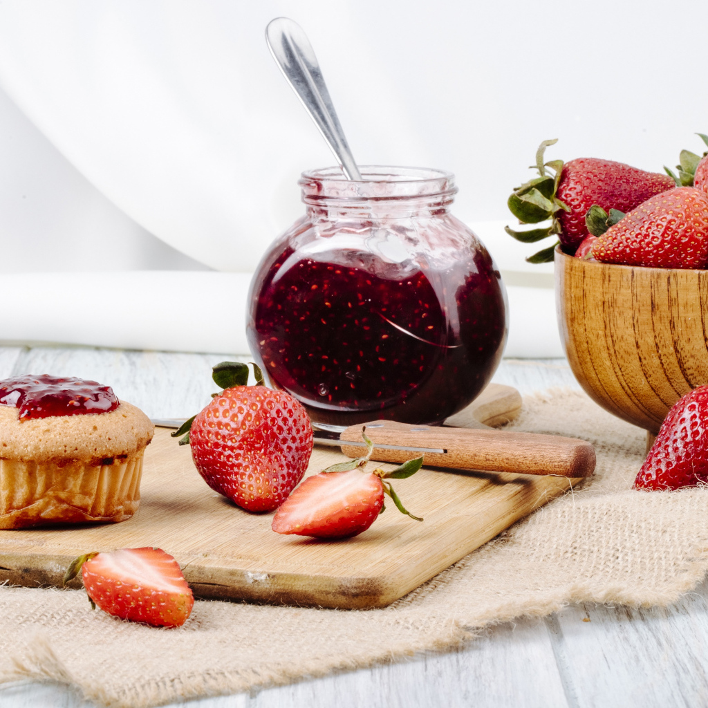 Кекс со свежей клубникой и джемом на столе