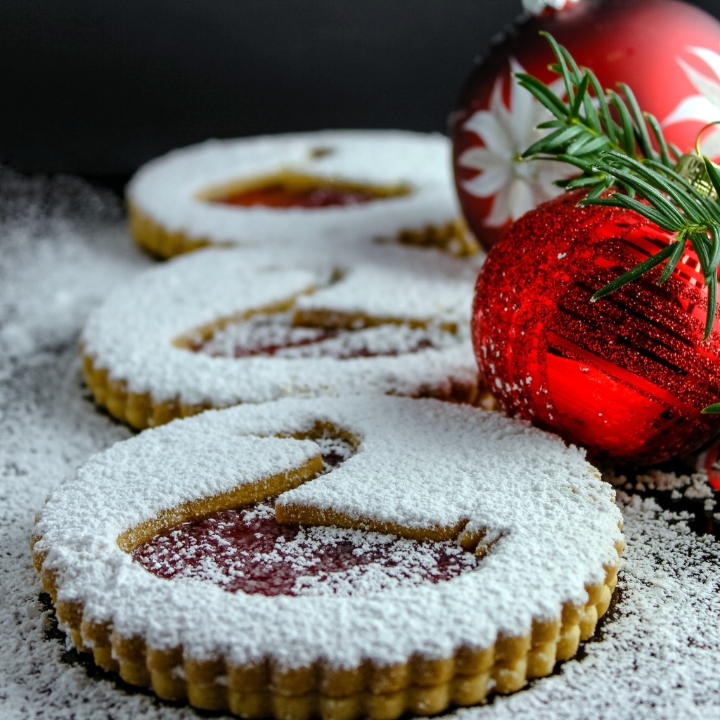 Вкусное сладкое печенье в сахарной пудре на столе с елочными игрушками