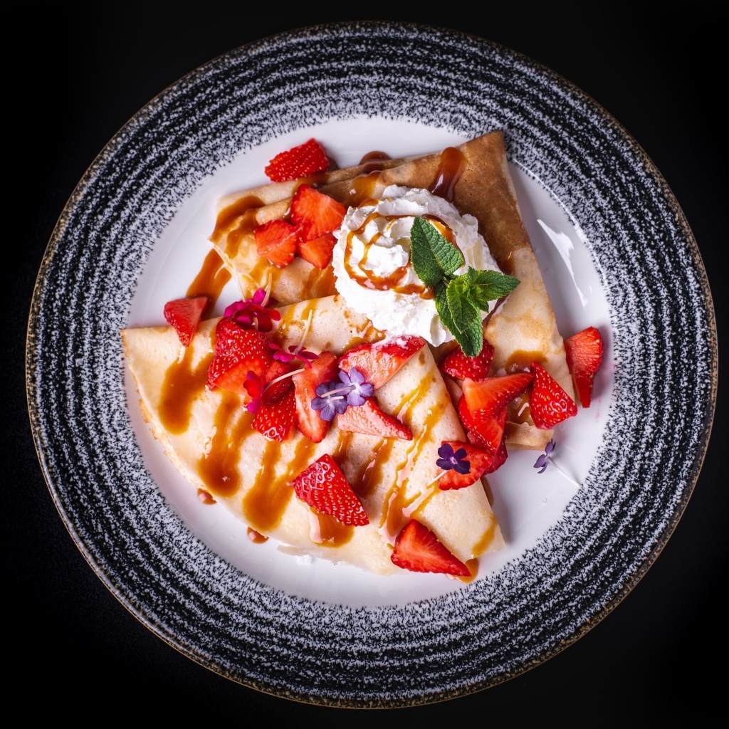 Вкусные сладкие блинчики на тарелке с ягодами