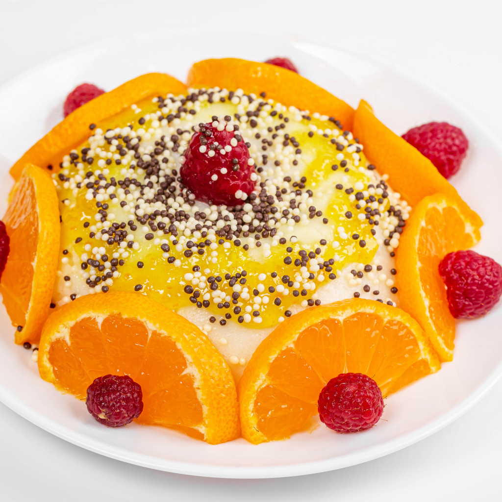 Десерт с кусочками апельсина и ягодами малины на белом фоне