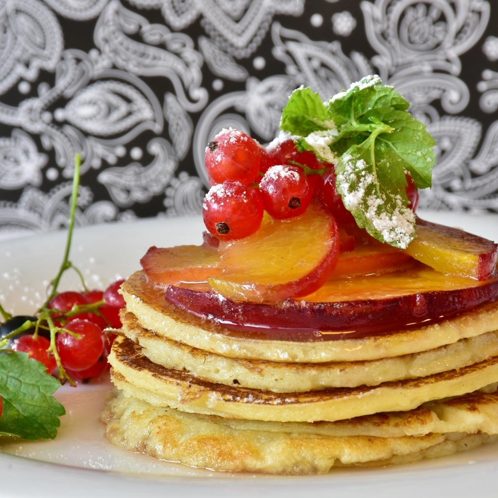 Оладьи на тарелке с ягодами смородины  и сливы