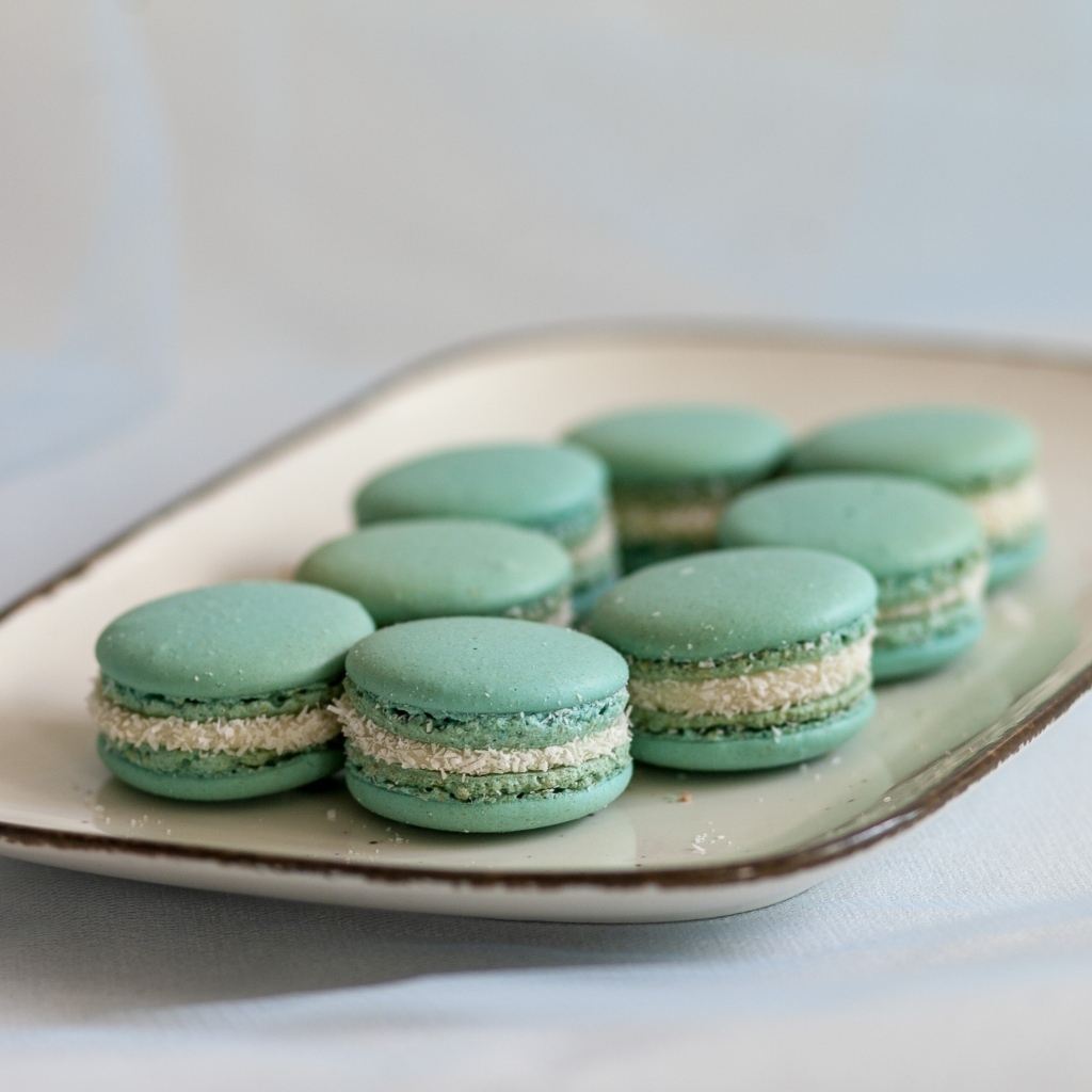 Зеленый десерт макаронс на большой тарелке на столе