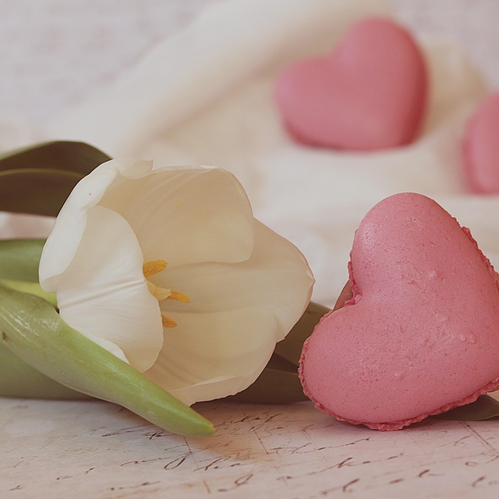 Десерт макарун в форме сердца на столе с тюльпаном