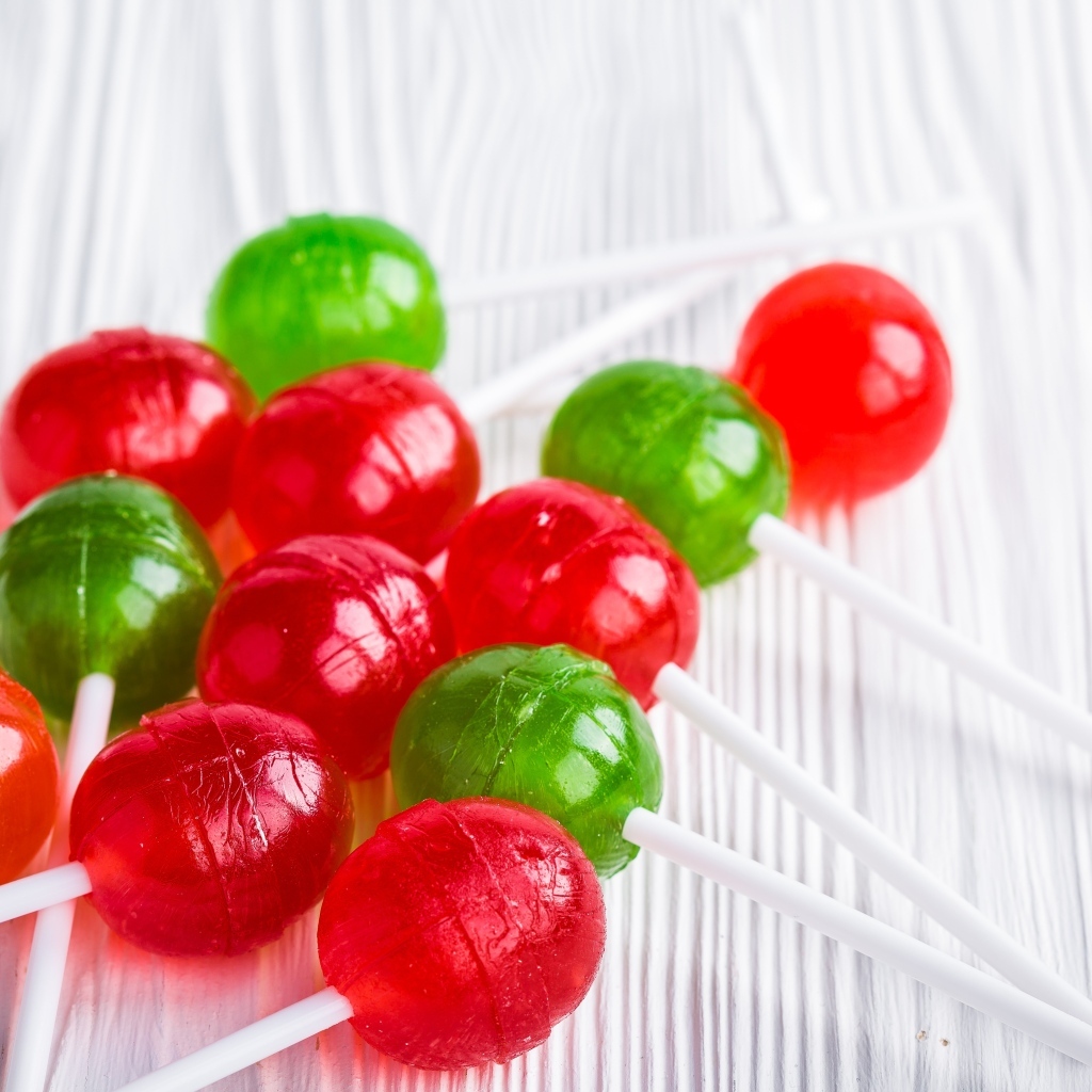 Разноцветные леденцы на палочке лежат на столе