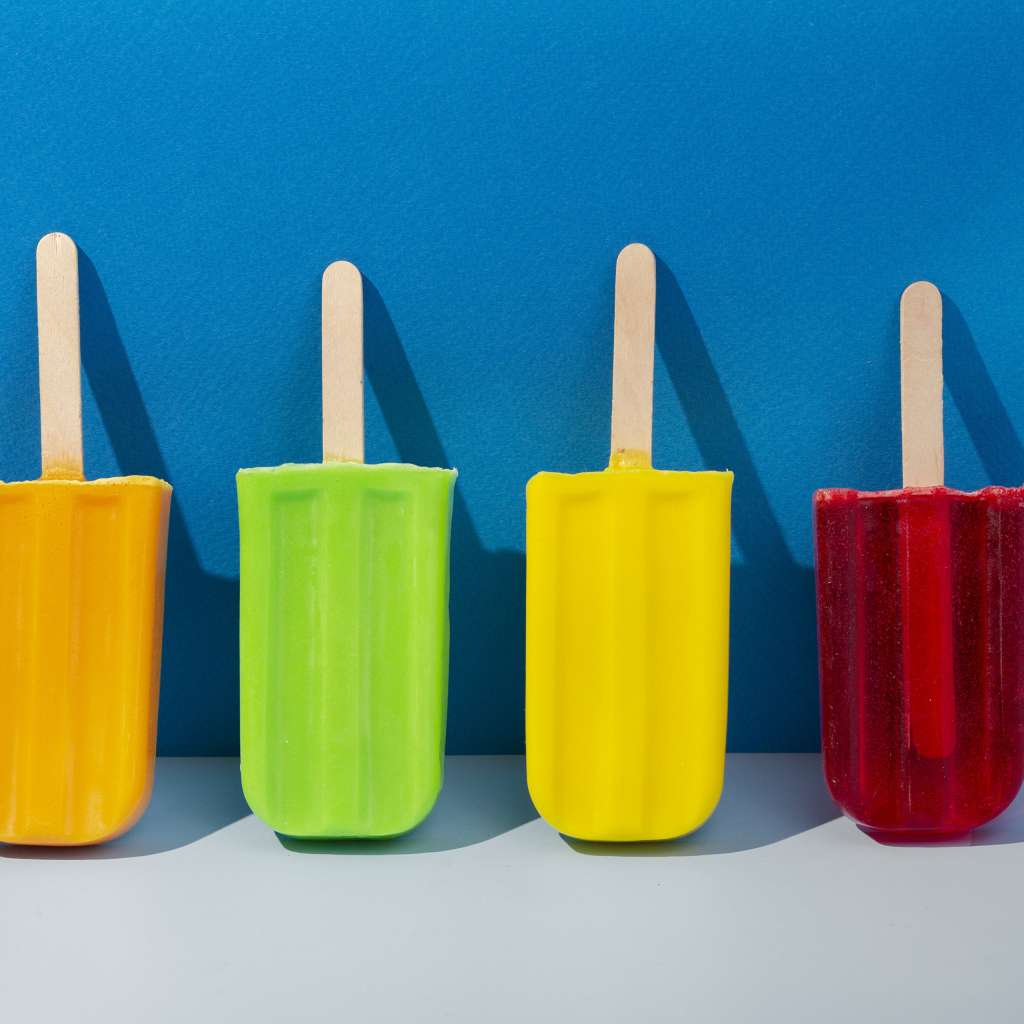 Разноцветное фруктовое мороженое на фоне голубой стены