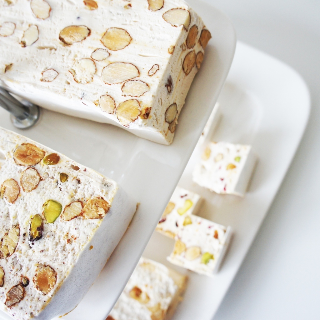 Нуга с орехами на белой тарелке