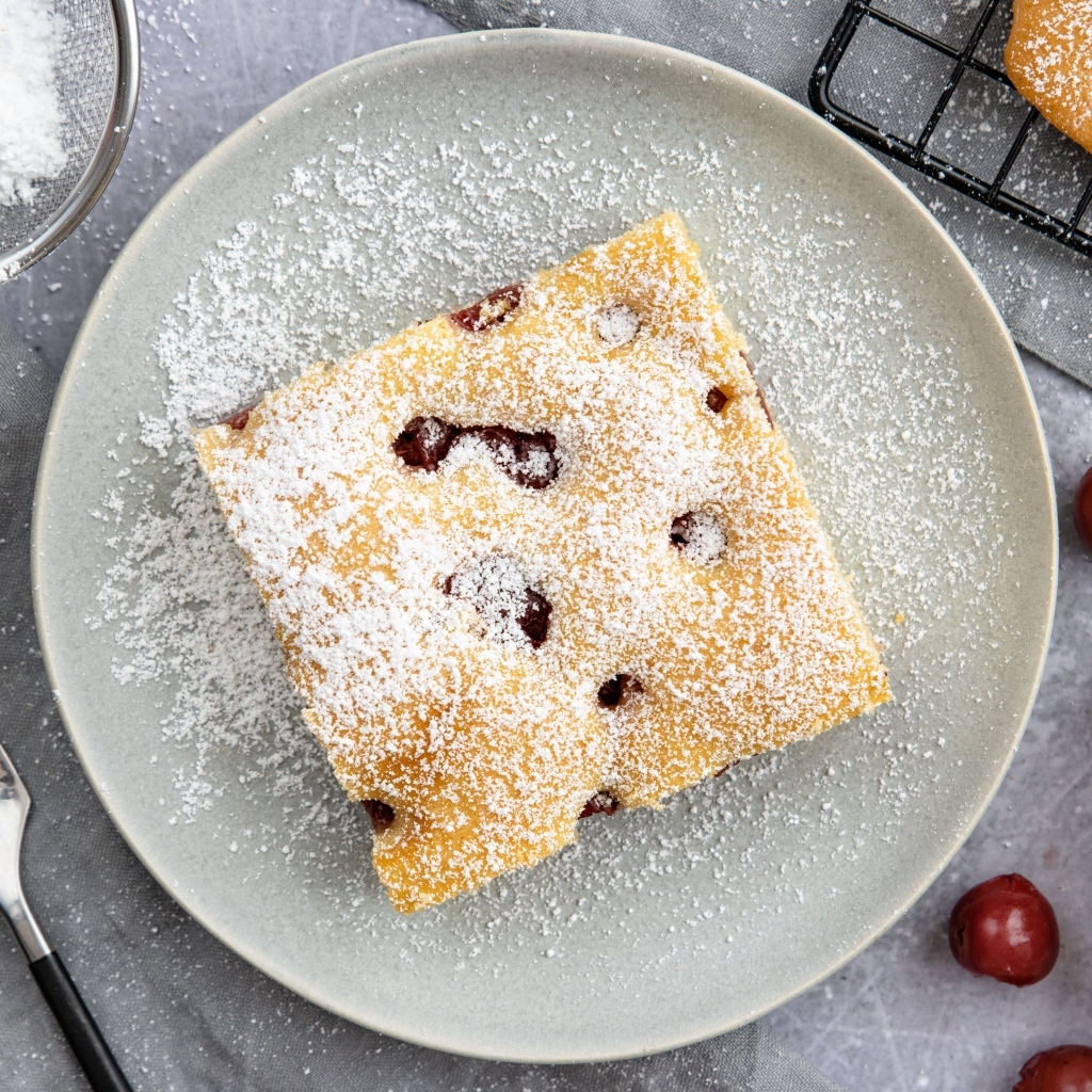 Кусок вишневого пирога на тарелке с сахарной пудрой