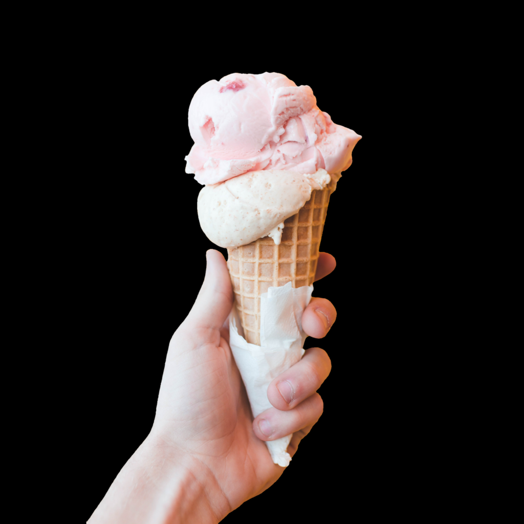 Розовое мороженое в рожке в руке на черном фоне