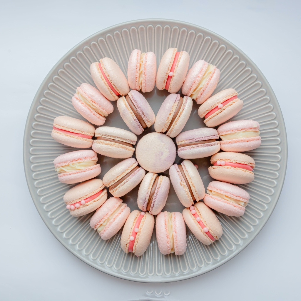 Розовый десерт макарон на большой тарелке