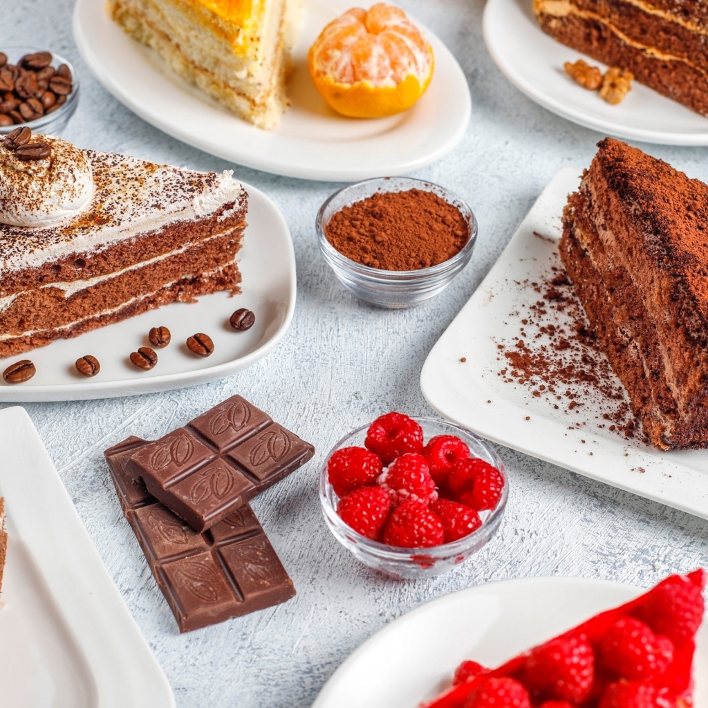 Сладкие куски торта на столе с шоколадом и ягодами