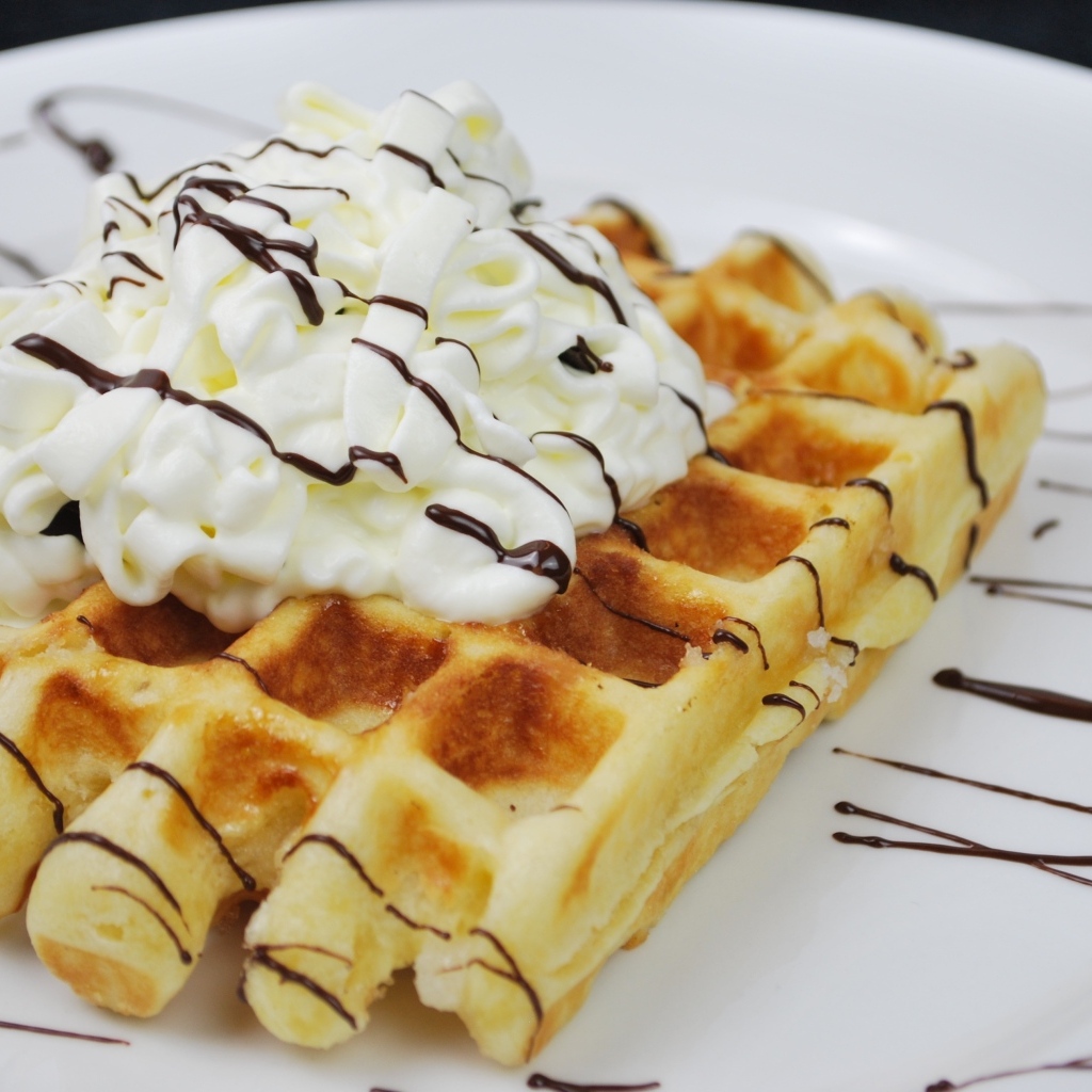 Сладкая вафля со сливками на белой тарелке