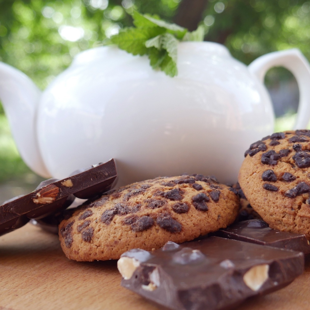 Чайник на столе с печеньем и шоколадом