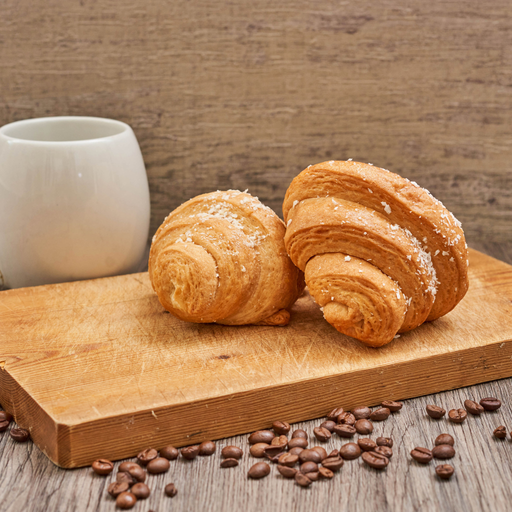 Два круассана на доске с кофейными зернами