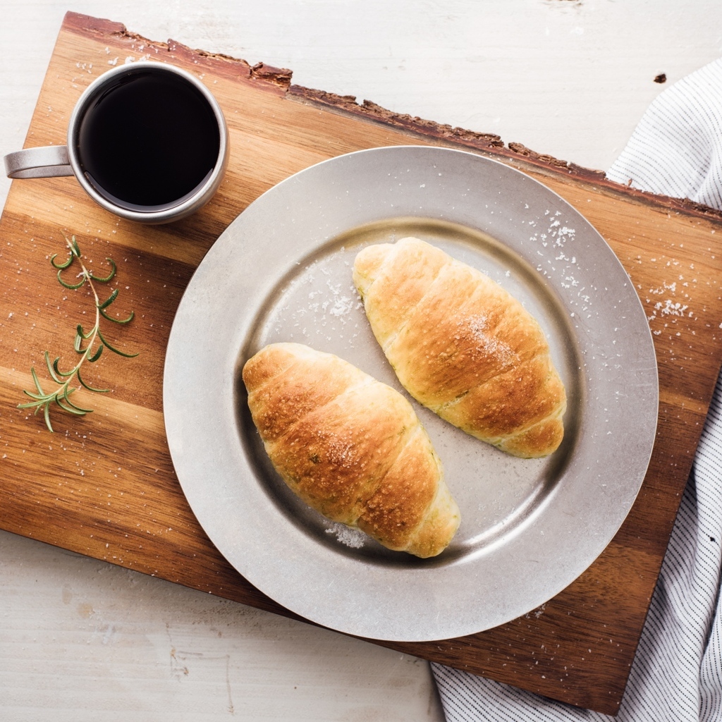 Два круассана на тарелке с чашкой кофе