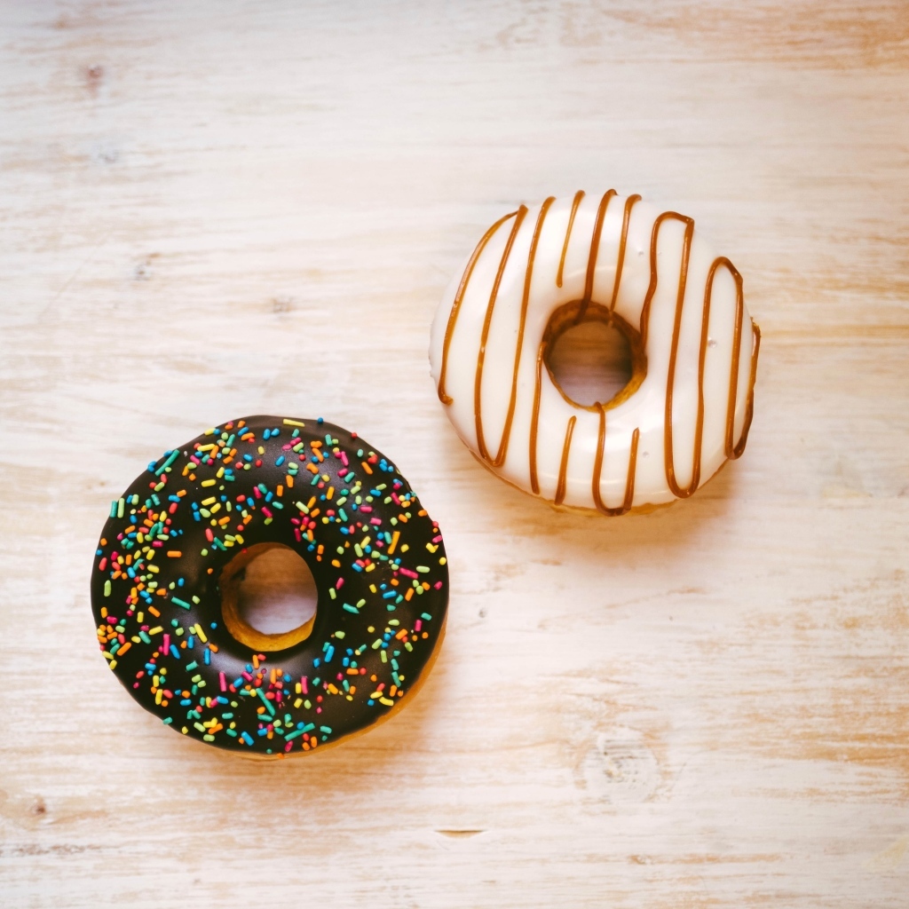 Два пончика в глазури на деревянном столе