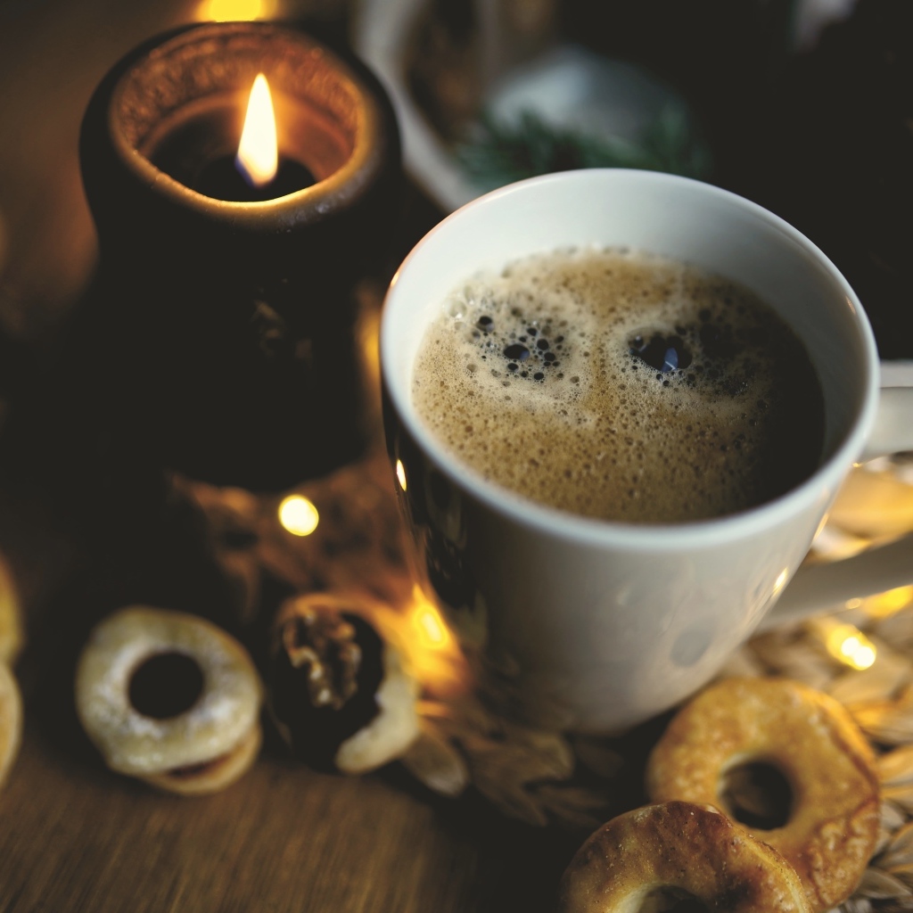 Чашка кофе на столе со свечой и печеньем