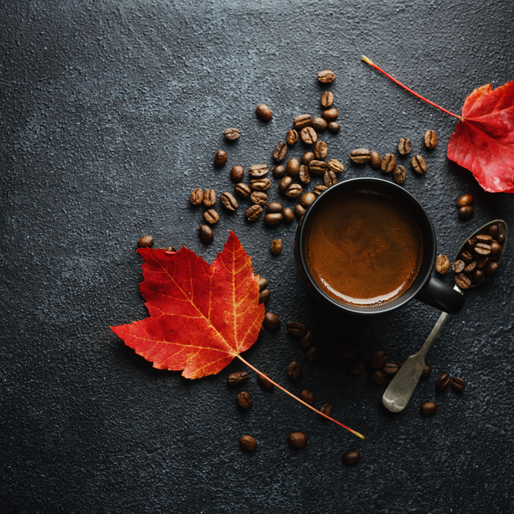 Чашка кофе на столе с зернами и желтыми листьями