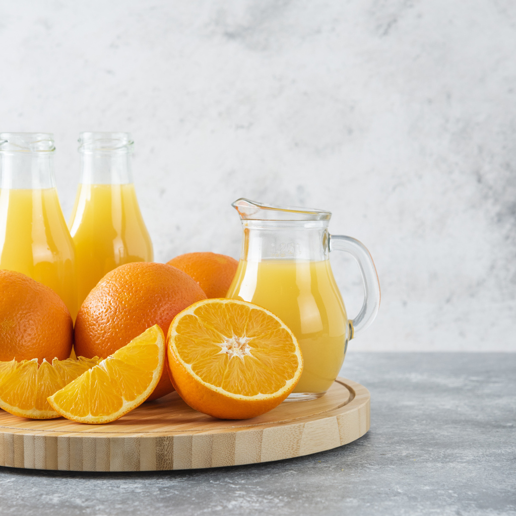 Свежевыжатый сок на столе с апельсинами