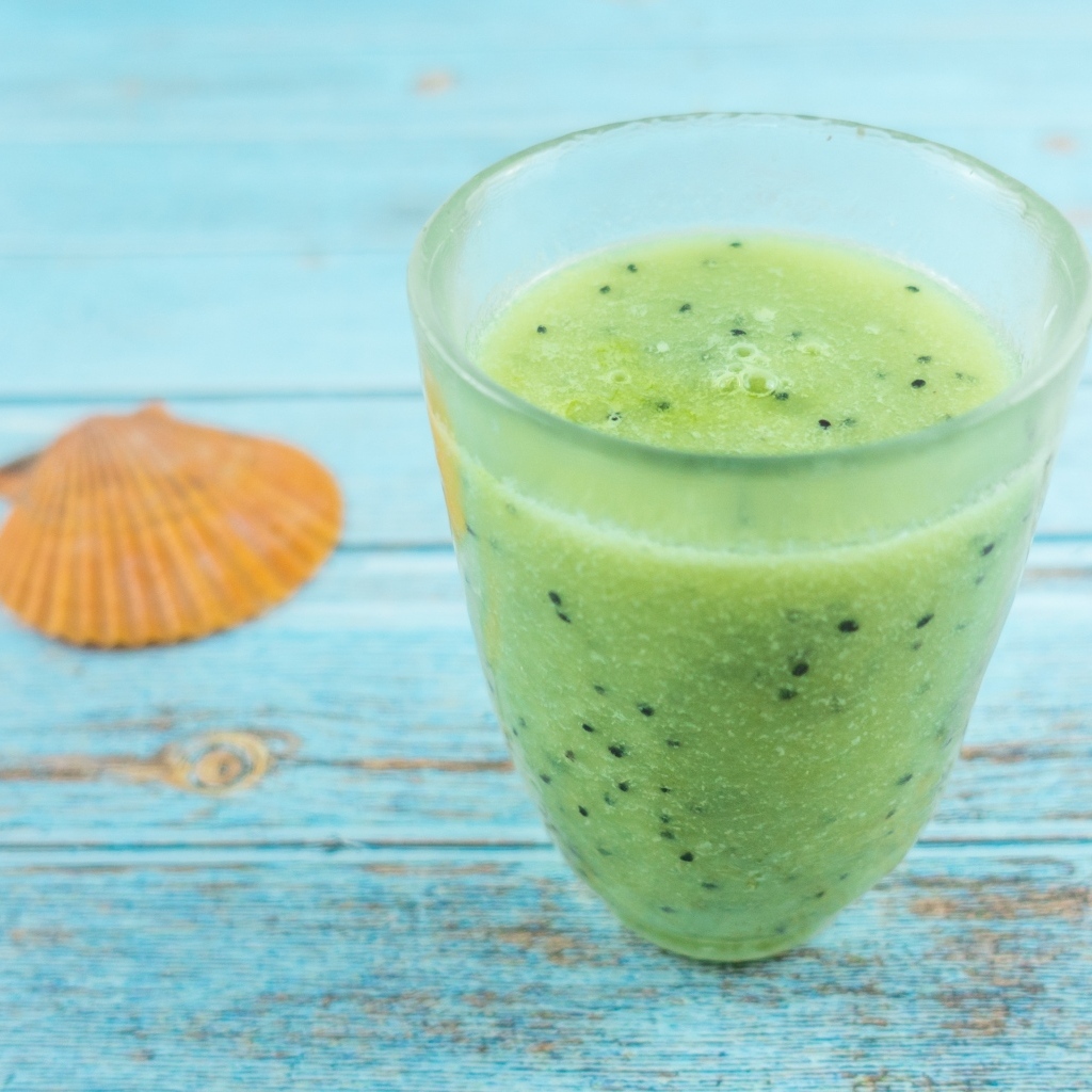 Фруктовый зеленый смузи на голубом столе