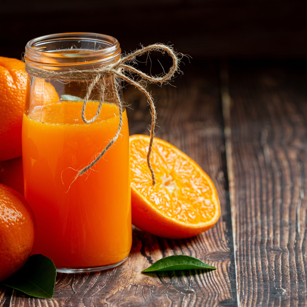 Банка свежего сока на столе с мандаринами