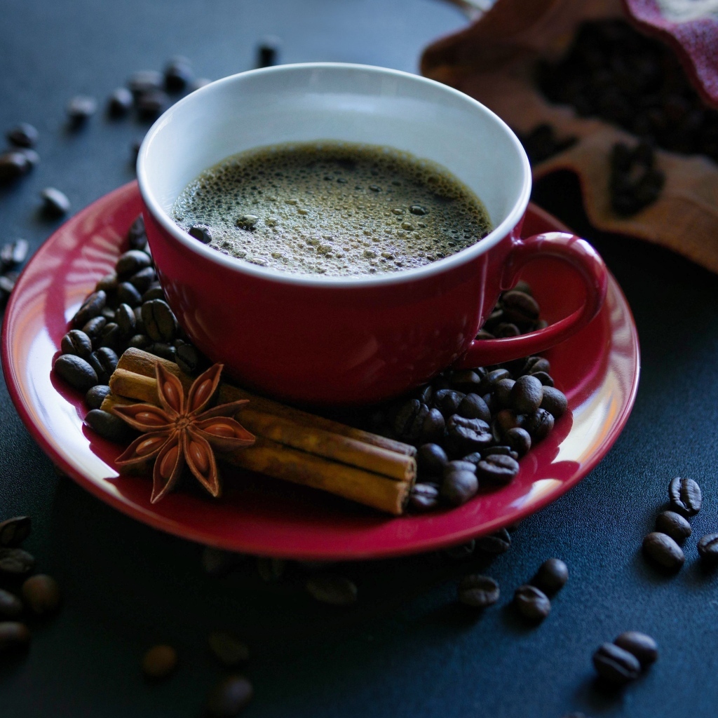 Красная чашка кофе на столе со специями и зернами