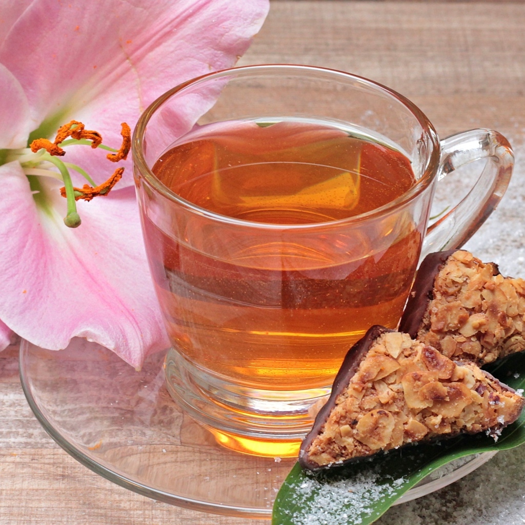 Чай на столе с розовой лилией и конфетами