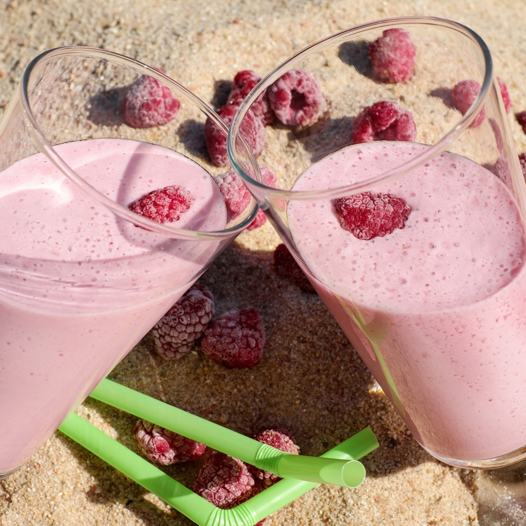 Два стакана ягодного смузи с малиной на песке 