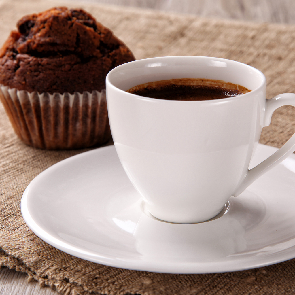 Белая чашка кофе на столе с кексом