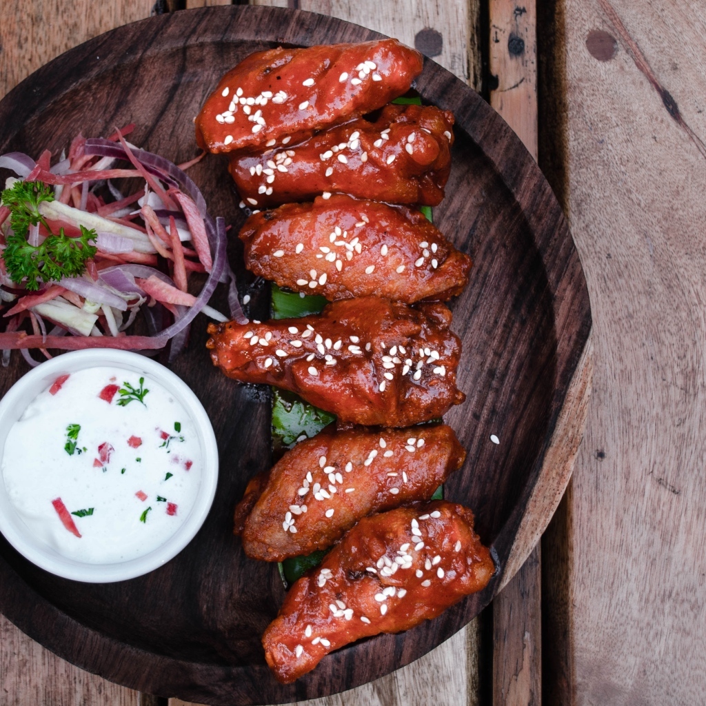 Запеченные куриные крылышки с соусом на тарелке