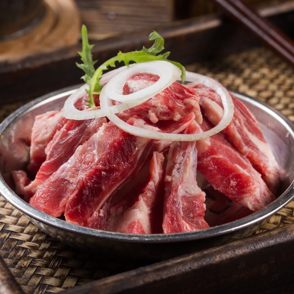 Свежие свиные ребра с луком в миске