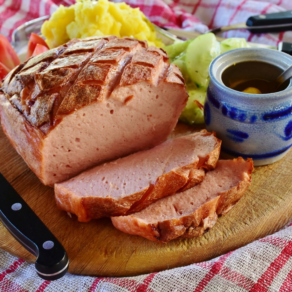 Мясной хлеб на столе с ножом и овощами