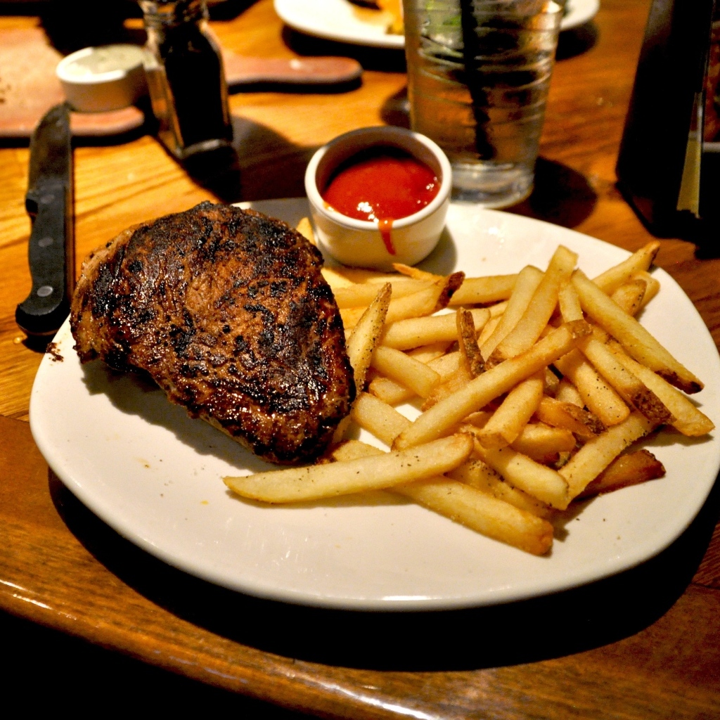 Кусок жареного мяса на тарелке с картофелем фри 