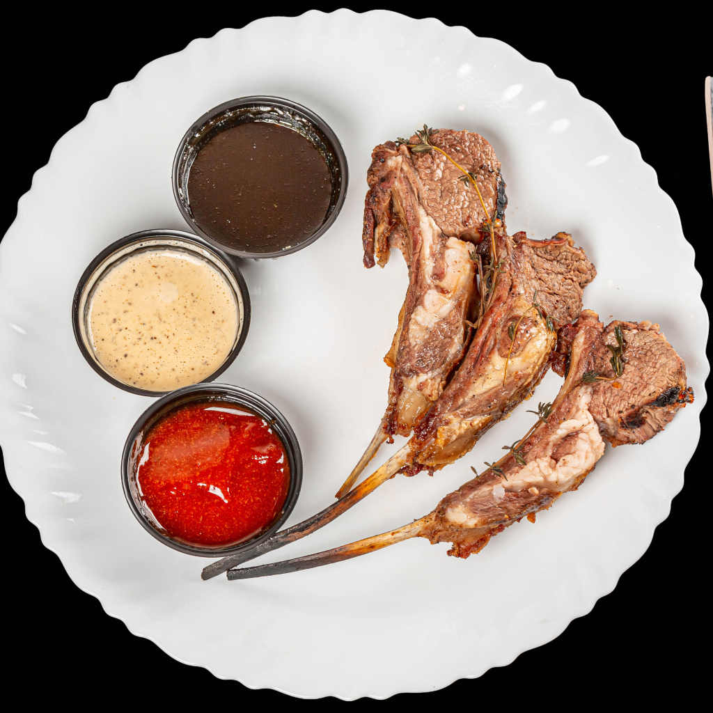 Свиные ребра с соусом на белой тарелке 