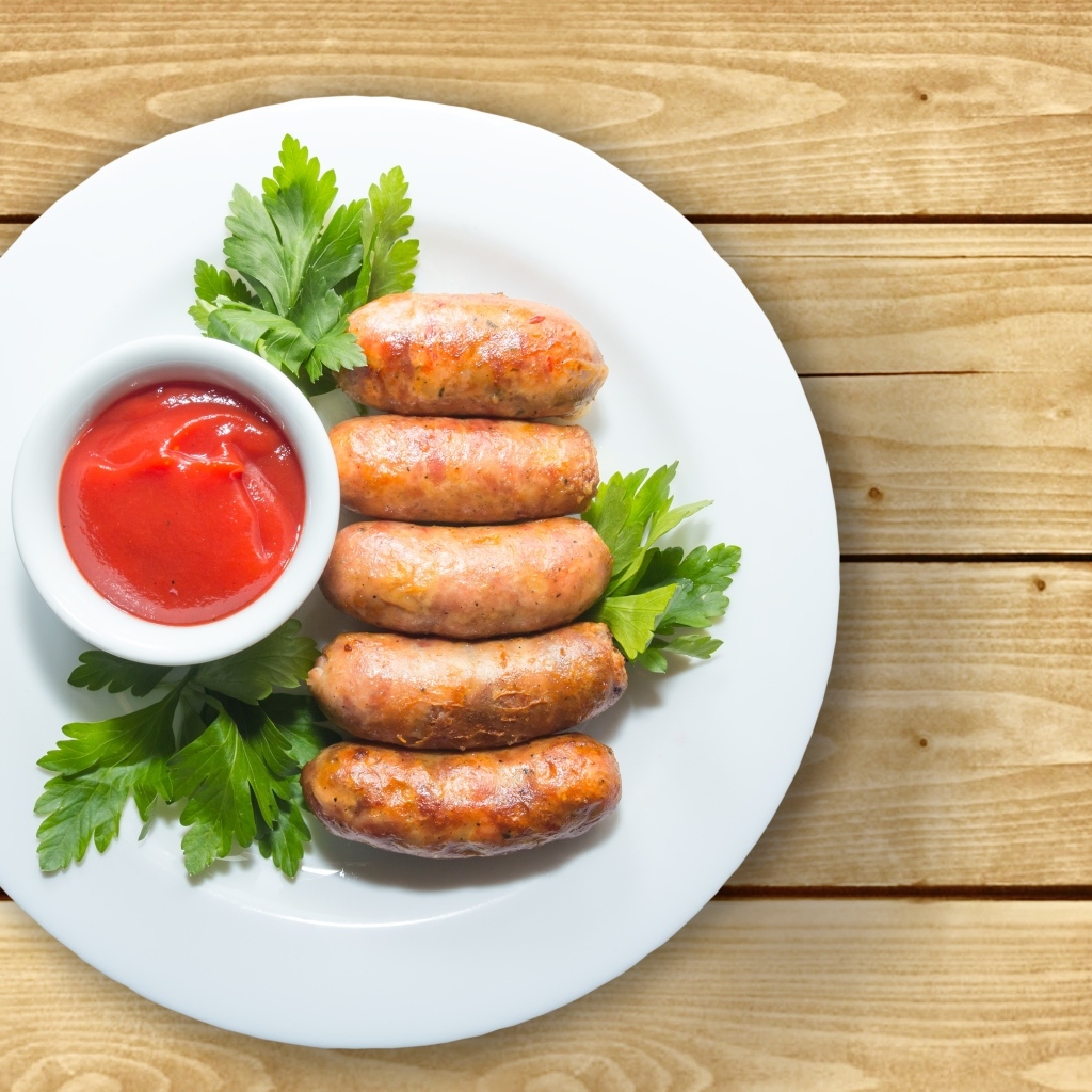 Сардельки на тарелке с соусом и петрушкой