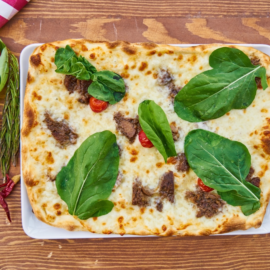 Мясная пицца с сыром и зелеными листьями