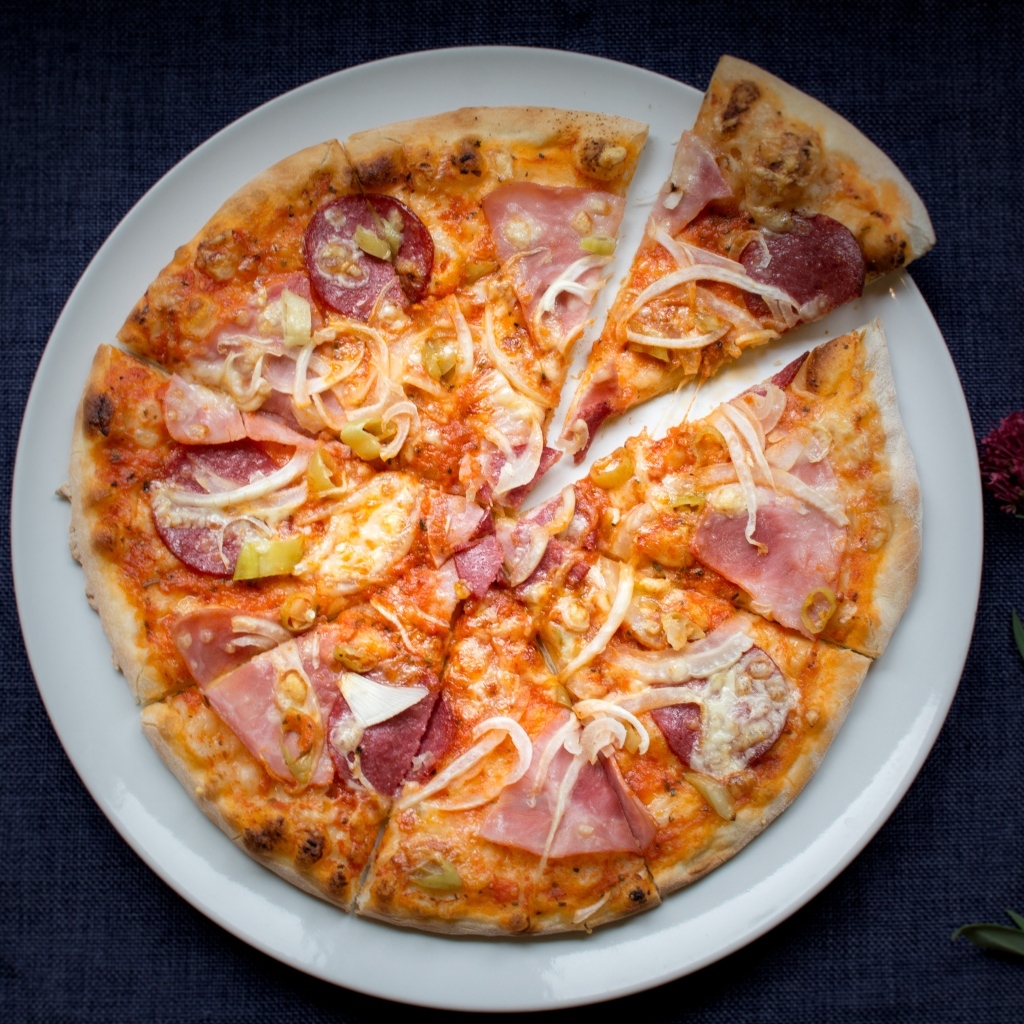 Нарезанная пицца на белой тарелке