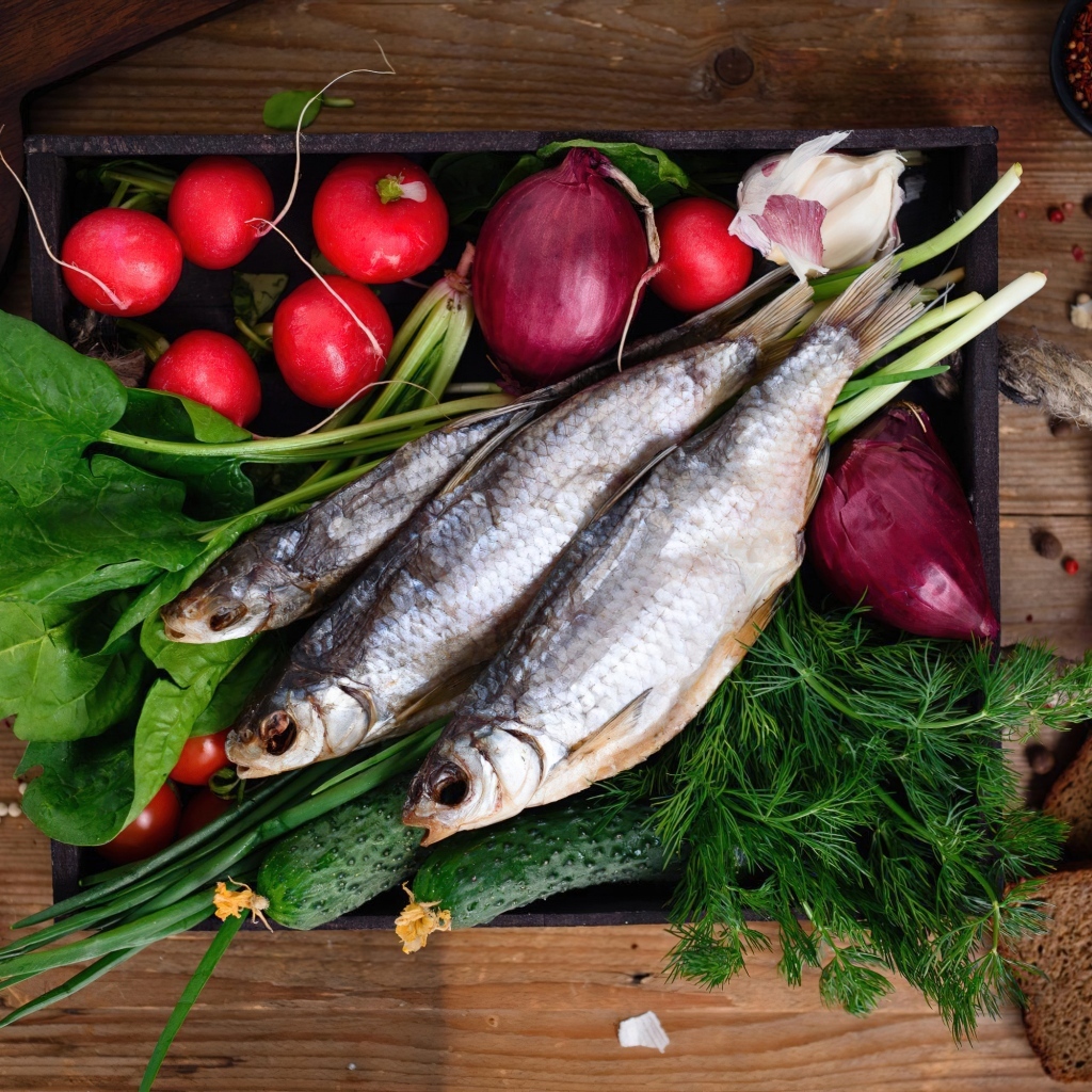 Сушеная рыба на столе с овощами и зеленью 