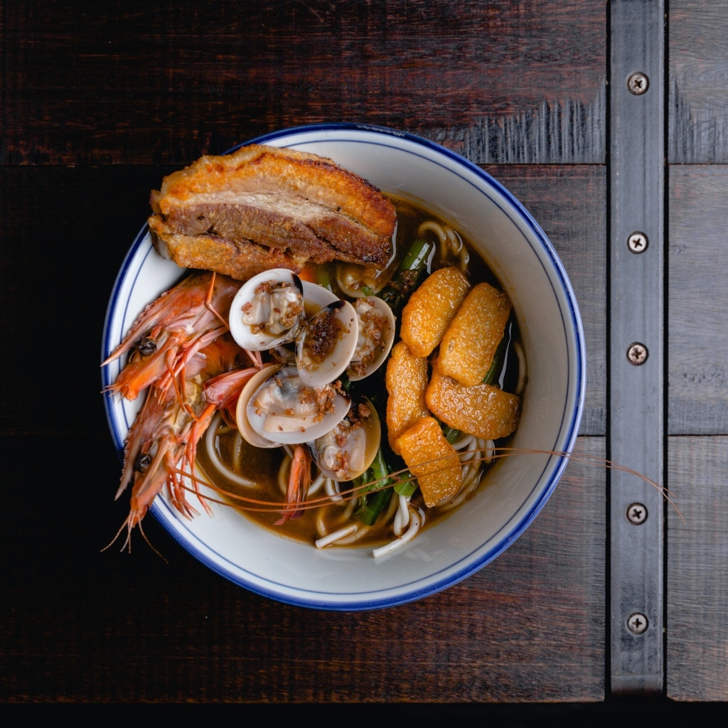 Суп с лапшой и морепродуктами на деревянном столе