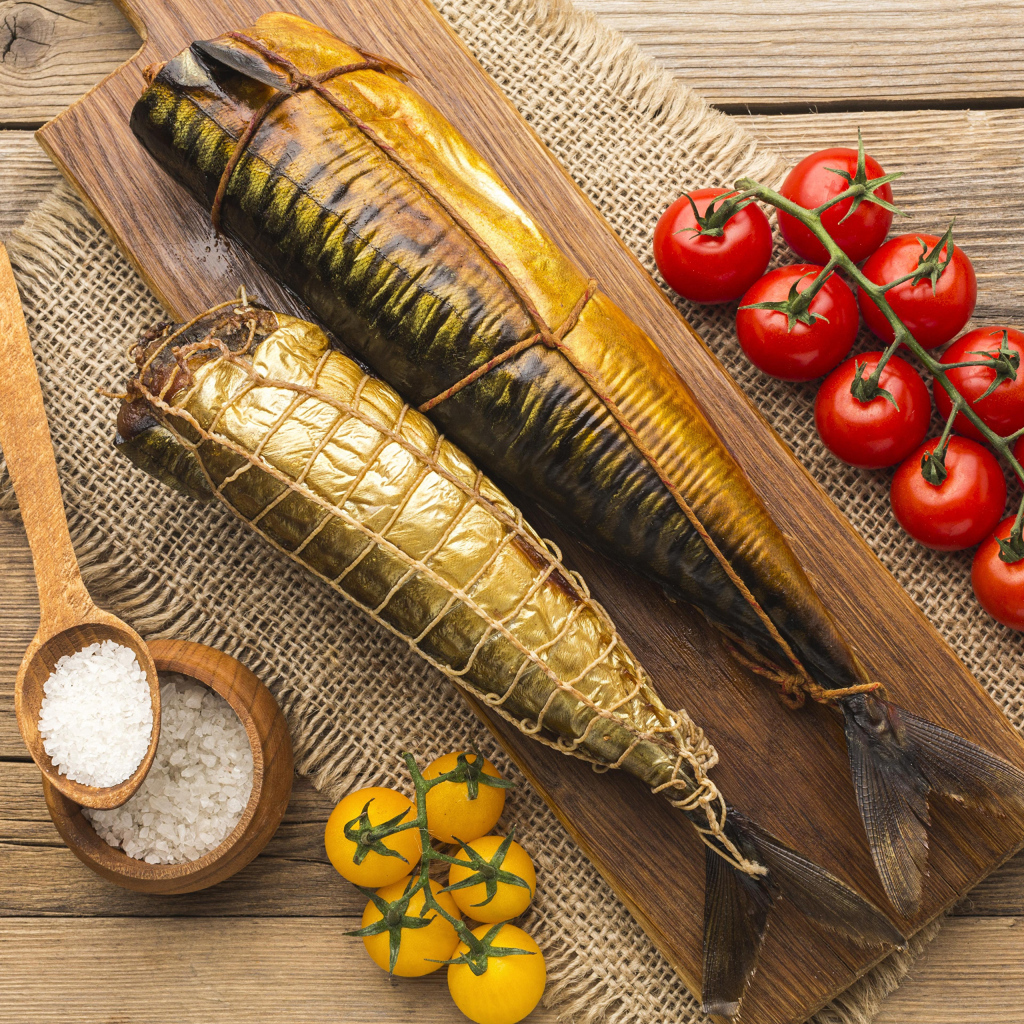 Две копченые скумбрии на столе с помидорами