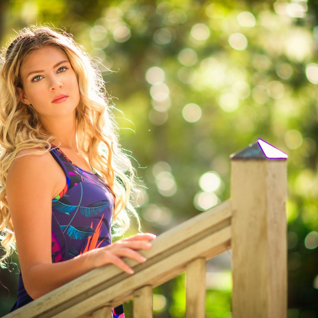 Красивая блондинка стоит у перил