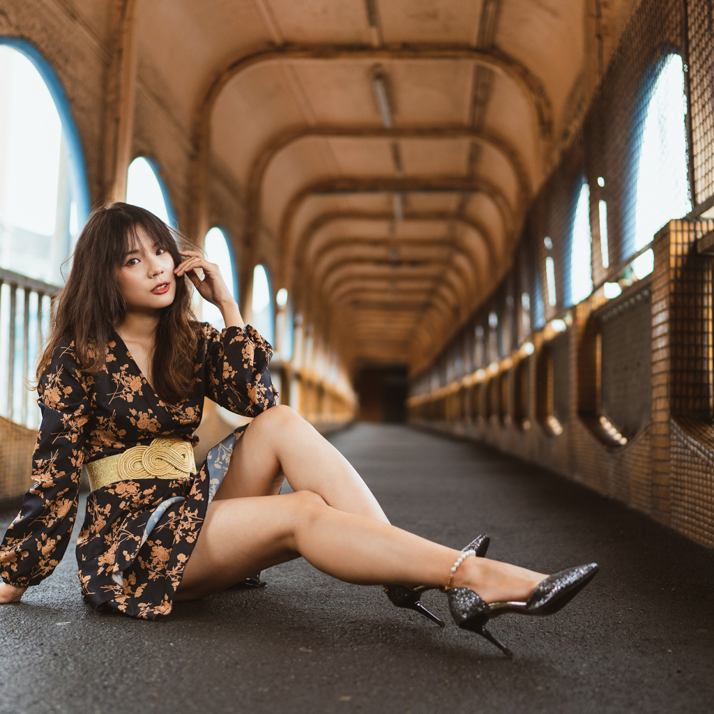 Девушка в красивом коротком платье сидит на полу