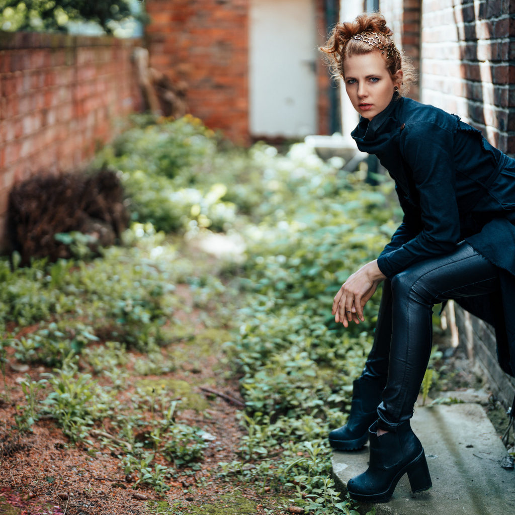 Девушка в черном наряде сидит на окне