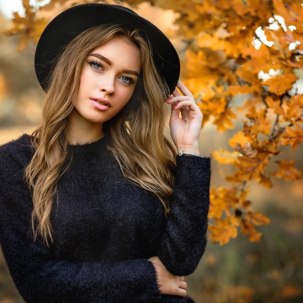 Девушка в черной шляпе стоит у дуба