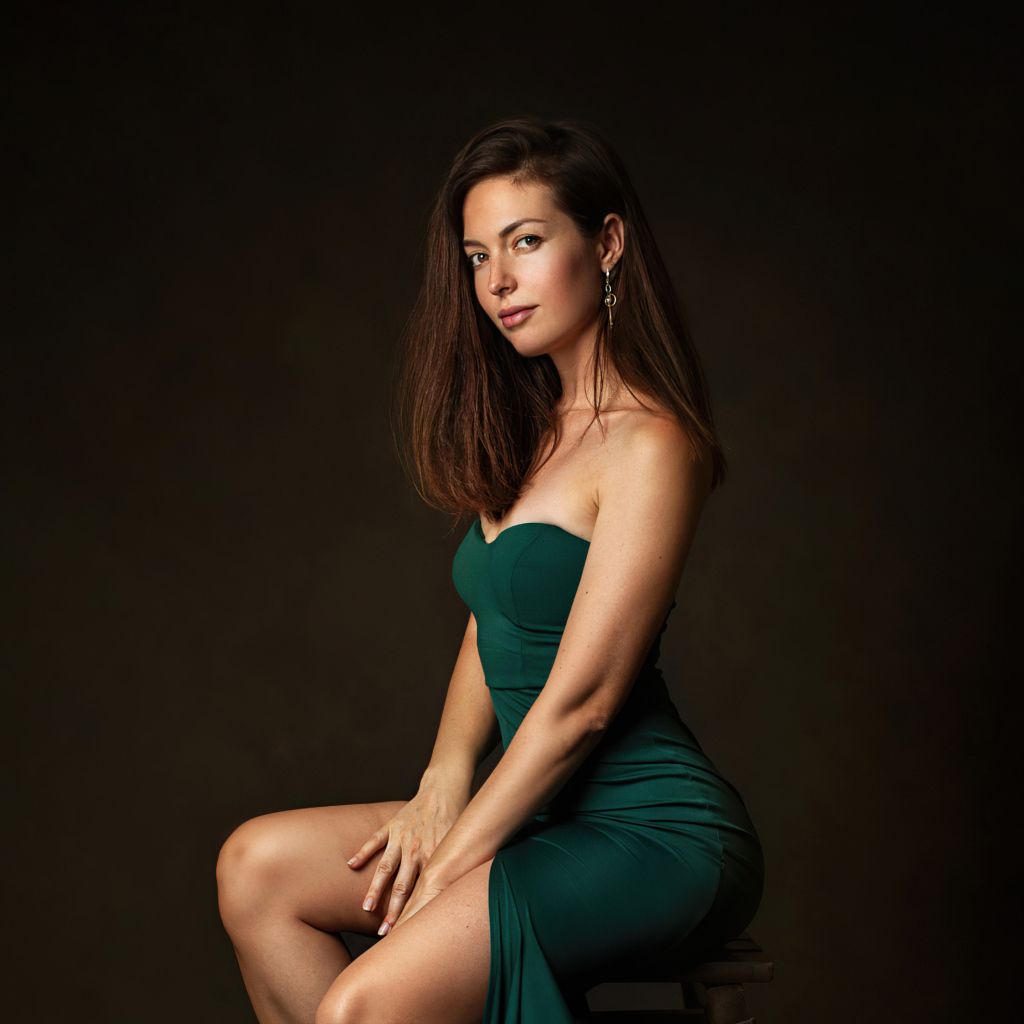 Девушка в зеленом платье сидит на стуле