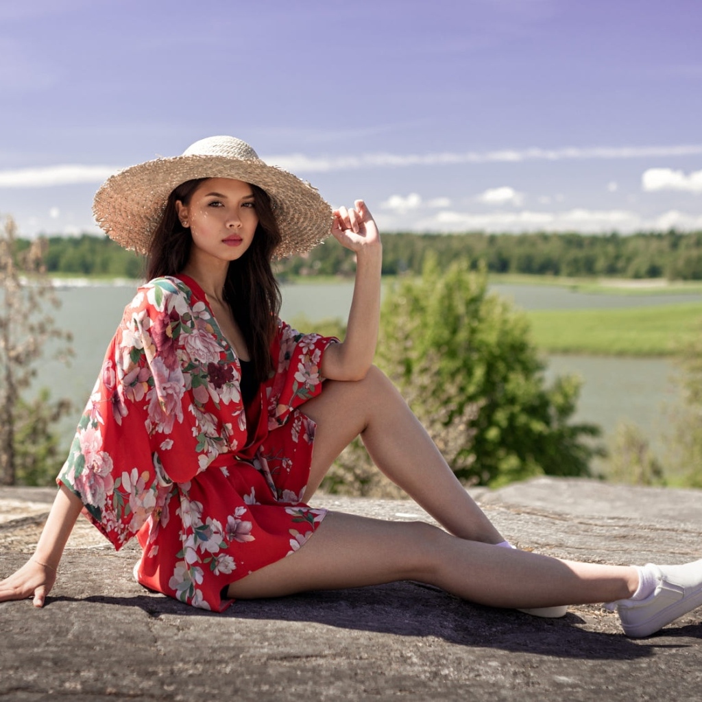 Девушка азиатка в шляпе лежит на камне