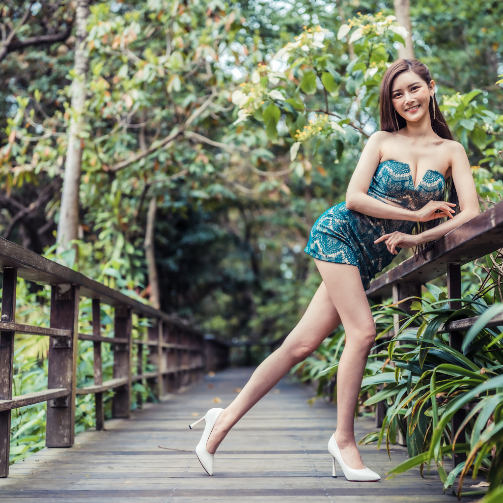 Девушка азиатка в коротком платье у перил на мосту