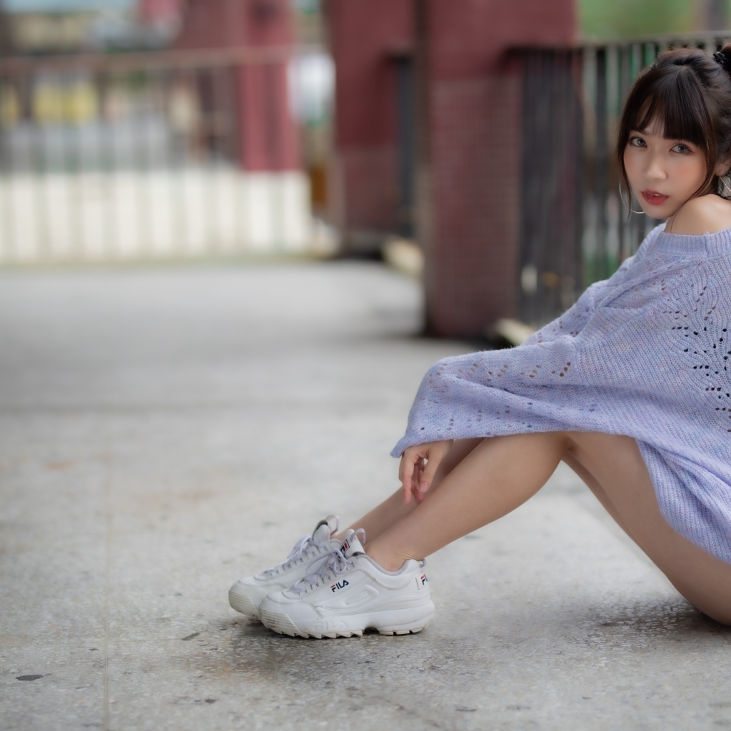 Девушка азиатка в свитере и белых кроссовках 